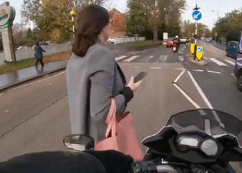 Wie is er fout? Motorrijder tikt voetganger aan die op haar telefoon staart (video)